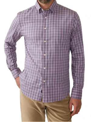 A man is wearing the Faherty Movement Sport Shirt, a long-sleeve button-up made from wrinkle-resistant Supima cotton, featuring a pink and blue plaid pattern. He pairs it with beige pants.