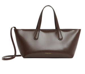 Mansur Gavriel's Mini Everyday is a brown leather handbag crafted from Italian spazzolato leather, featuring dual handles and an adjustable crossbody strap, set against a white background.