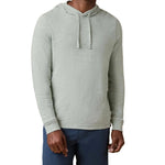 A person wears the Faherty Sunwashed Slub Hoodie in light gray with drawstrings and dark blue pants, standing against a white background.
