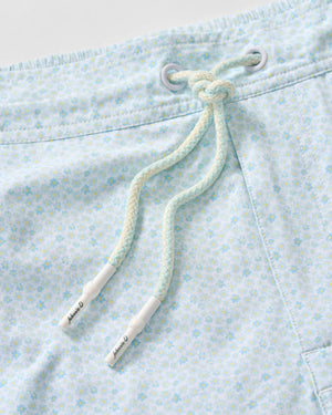 Close-up of the Johnnie-O Anemone Swim Trunks in light blue, showcasing a subtle floral pattern and braided drawstrings threaded through metal eyelets. Crafted from a comfortable poly/spandex blend, these trunks combine style and flexibility—perfect for fun prints and beach adventures.