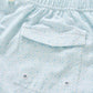Close-up of the Anemone Swim Trunks by Johnnie-O, made from a light blue patterned poly/spandex blend. These comfortable surf shorts feature an elastic waistband and a back pocket with two metal grommets—perfect for easy-wearing style and fun, vibrant prints.