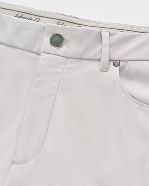 Close-up of the front pocket and waistband on a pair of light gray Johnnie-O Cross Country Flex Pants, crafted from stretch knit fabric with a button, belt loop, and visible stitching details.
