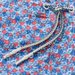 Close-up of the Johnnie-O Freesia Swim Trunk, showcasing a playful blue and red floral print, navy and white braided drawstring with metal grommets, and a 7" inseam.