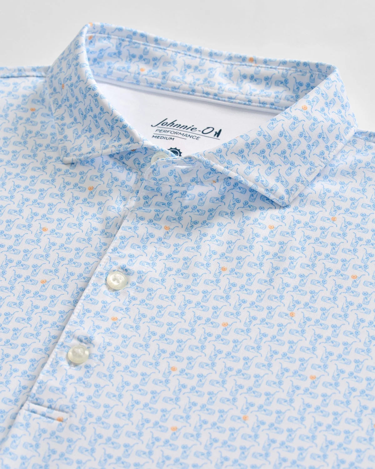 Johnnie-O Minty Polo: A light blue short-sleeve men's performance polo shirt featuring a subtle pattern of blue and orange illustrated sea creatures, partial button placket, and a visible Johnnie-O brand label inside the collar.