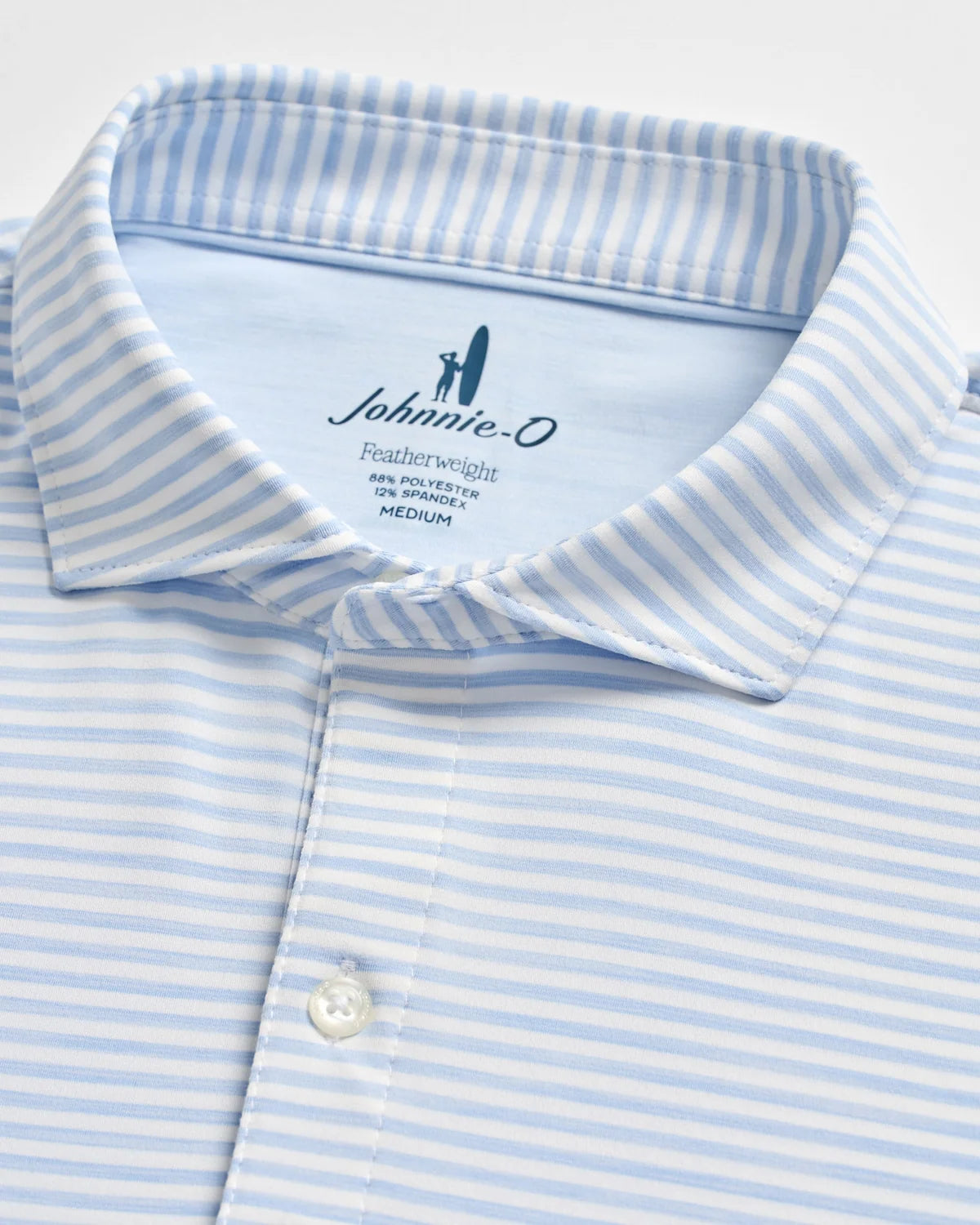 Close-up of a light blue and white striped collared shirt with buttons, featuring the Johnnie-O brand label and size details inside the collar—crafted in the signature performance style of the Johnnie-O Seymour Polo for enhanced comfort and sun protection.