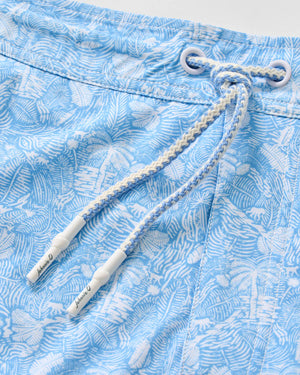 Close-up of the Johnnie-O Swingin Swim Trunks in blue, showcasing a white tropical leaf pattern and a white-and-blue braided drawstring threaded through metal eyelets—perfect swimwear for those who love fun prints.