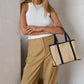 Person with long hair wearing a white sleeveless top and tan pants, holding the Bembien Margot Bag, Mini while leaning against a wall.