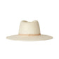 The Sherman Hat by Janessa Leone is a wide-brimmed, off-white packable straw fedora with a beige band and gold accent, shown on a white background.
