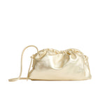 The Mansur Gavriel Mini Cloud Clutch is a golden satin bag with a gathered top and removable strap, crafted from Italian lamb leather, shown against a white background.