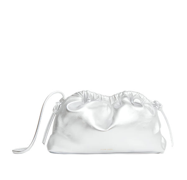 Mansur Gavriel's bestselling Mini Cloud Clutch is crafted from silver Italian lamb leather and features a ruched drawstring closure with a small loop handle against a white background. Customize it with a removable strap for versatile styling.