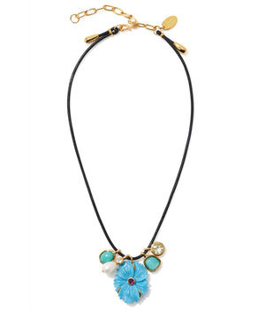 The Shibori Flower Necklace by Lizzie Fortunato features a black leather cord, a large blue floral pendant, imitation turquoise and white beads, gold charms, rhodolite stone accents, and an adjustable gold clasp.