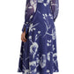 A person in an Erdem Long Sleeve Midi Dress with a blue carnation print and sheer sleeves, paired with black shoes, facing away.