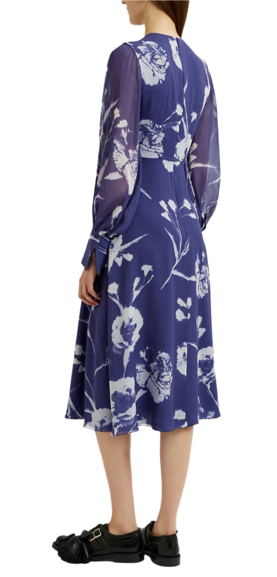 A person in an Erdem Long Sleeve Midi Dress with a blue carnation print and sheer sleeves, paired with black shoes, facing away.