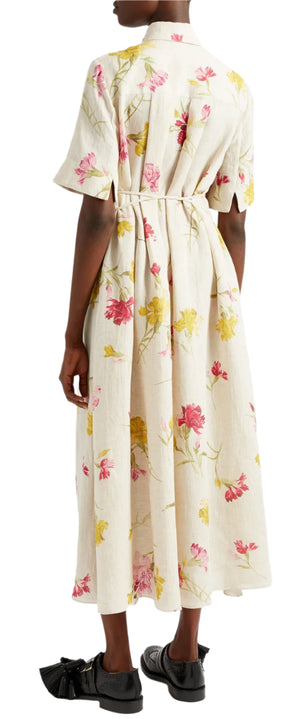 An individual is seen from behind wearing Erdem's Short Sleeve Linen Shirt Dress, adorned with pink and yellow flowers against a light background. The ankle-length dress features a tie-fastening belt at the waist.