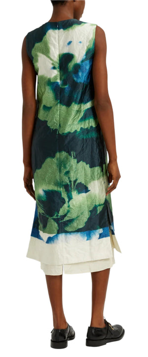 A person stands against a white background wearing an Erdem Sleeveless Pencil Midi Dress, showcasing abstract green and blue patterns, paired with black shoes.