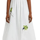 Someone is wearing an Erdem Short Sleeve Embroidered Shirt Dress, featuring a white design with embroidered carnations, paired with black strappy shoes.