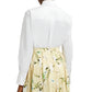 An individual is seen from behind wearing an oversized white Long Sleeve Embroidered Shirt by Erdem, tucked into a high-waisted, yellow floral skirt.