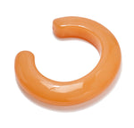 The Ridge Cuff by Lizzie Fortunato is a thick, glossy, orange crescent-shaped bracelet with an open end, resembling a chunky domed cuff.
