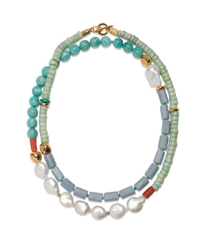 The Cabana Necklace by Lizzie Fortunato features turquoise, green, and blue beads, gold accents, red details, and white pearl-like beads in a stylish layered design.