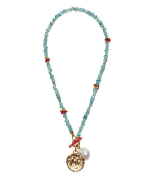 The Crystal Cala Necklace by Lizzie Fortunato features turquoise beads, red accents, blue apatite beads, a gold coin pendant, and a freshwater pearl charm.