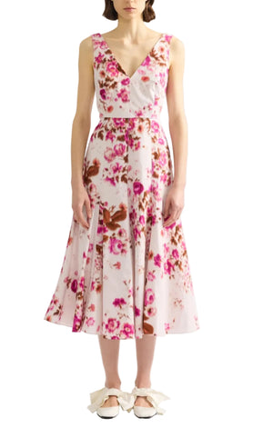 A woman wearing the Erdem Rose Bouquet Fit and Flared Midi Dress, a sleeveless, V-neck, midi cotton poplin dress with a pink roses pattern, paired with white shoes featuring bow details.