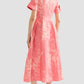 A woman faces away, wearing the Erdem Rose Bouquet Linen Chine Midi Shirt Dress with short sleeves and white bow slip-ons, set against a plain light background.