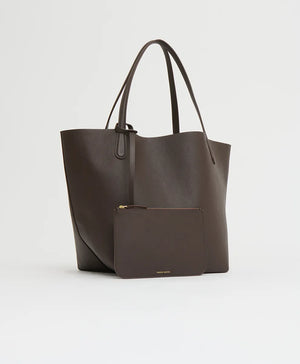 The Mansur Gavriel Everyday Soft Tote in dark brown leather, featuring thin handles, is displayed on a plain light background with a matching zippered pouch placed in front.