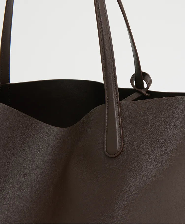 Close-up of the Mansur Gavriel Everyday Soft Tote, crafted from dark brown Italian calf leather with two handles, highlighting its textured material and minimalist design.