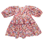 The Girls' Maribelle Dress by Pink Chicken features puffy long sleeves, a flared skirt, and a colorful floral print in pink, red, blue, and yellow—perfect as a spring dress for your little one.