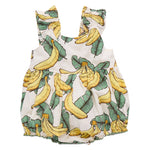 The Pink Chicken Baby Girls' Via Bubble is crafted from soft cotton cambric and features a playful yellow banana and lush green leaf print on a crisp white background.