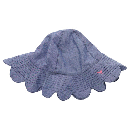 The Pink Chicken Baby Scallop Sun Hat is a blue chambray sun hat with a scalloped brim and a small pink embroidered detail on the side, shown on a white background.