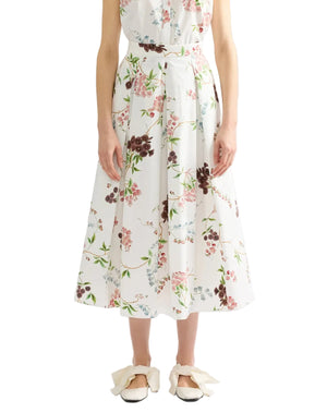 A person wearing Erdem's French Chintz Cotton Midi Skirt paired with white shoes featuring large bows.