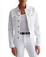 A person is wearing the AG Robyn Denim Jacket, a women's jean jacket in AG Cloud Soft Denim™, over a white tank top, paired with white jeans and a black belt.