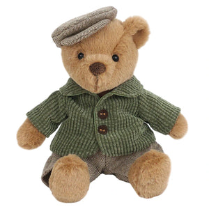 Bernard Bear by Mon Ami sits upright against a white background, dressed in a green corduroy jacket, brown striped pants, and a matching flat cap.