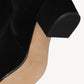 Close-up of the Staud Aimee Short Boot, a black suede ankle bootie with a side zipper, featuring a tan sole and the brand logo stamped on the bottom.
