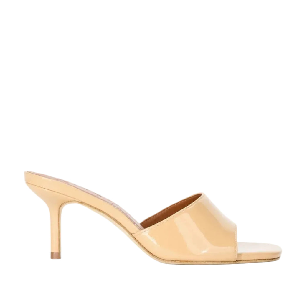 The Staud Bea Mule, shown in profile against a white background, is a single nude patent leather mule with a wide strap, square toe, and mid-height stiletto heel.