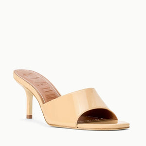 The Staud Bea Mule is a beige patent leather sandal featuring a square toe, open design, and thin high heel, shown against a white background.