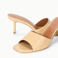 The Staud Bea Mule features a beige, glossy finish, square open toe, and low stiletto heel—a chic leather shoe for any occasion.