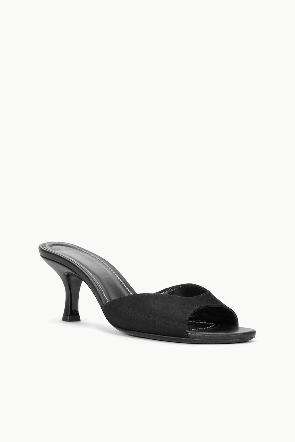 The Brigitte Satin Mule by Staud is a black open-toe mule sandal with a mid stiletto heel and minimalist design, ideal for versatile styling.