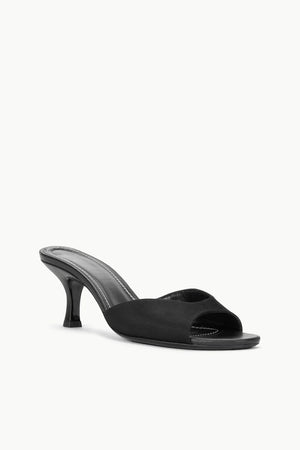 The Brigitte Satin Mule by Staud is a black open-toe mule sandal with a mid stiletto heel and minimalist design, ideal for versatile styling.