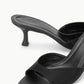 Close-up of the Brigitte Satin Mule by Staud, a black open-toe mule with a satin kitten heel and white stitching along the insole—ideal for versatile styling.