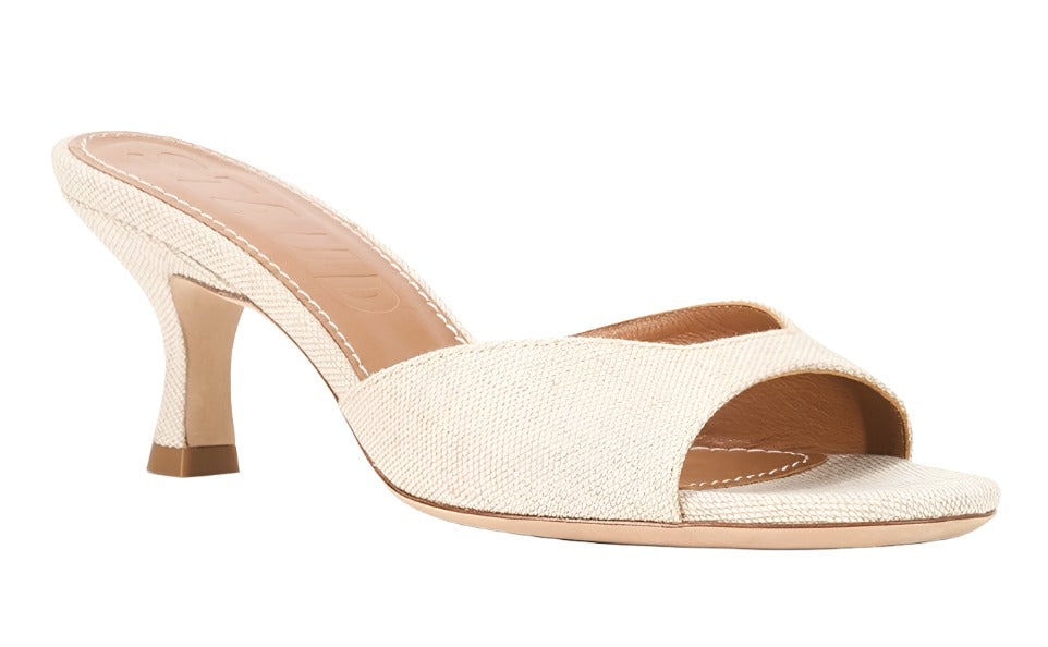 The Staud Brigitte Mule from Staud is a beige open-toe mule featuring a textured fabric upper and a modest kitten heel, ideal for versatile dressing.