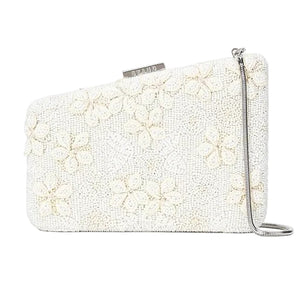 The Carmella Beaded Clutch by Staud is a rectangular white clutch featuring a floral beaded pattern, silver clasp, and a thin removable chain strap for versatile styling.