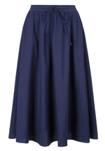 The Staud Eden Skirt, a navy blue poplin midi skirt featuring an adjustable drawstring waistband, is a summer essential that falls gracefully to knee length.