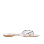The Staud Carrie Sandal features refined metallic silver leather straps that cross elegantly over the top and a low heel, displayed on a white background.