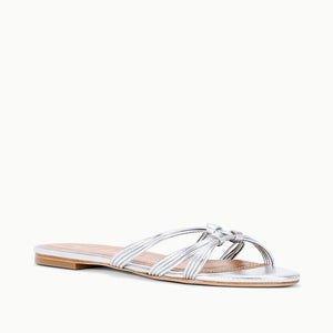 The Carrie Sandal by Staud is a flat silver strappy sandal with multiple thin, crisscrossing straps and an open toe, shown against a white background.