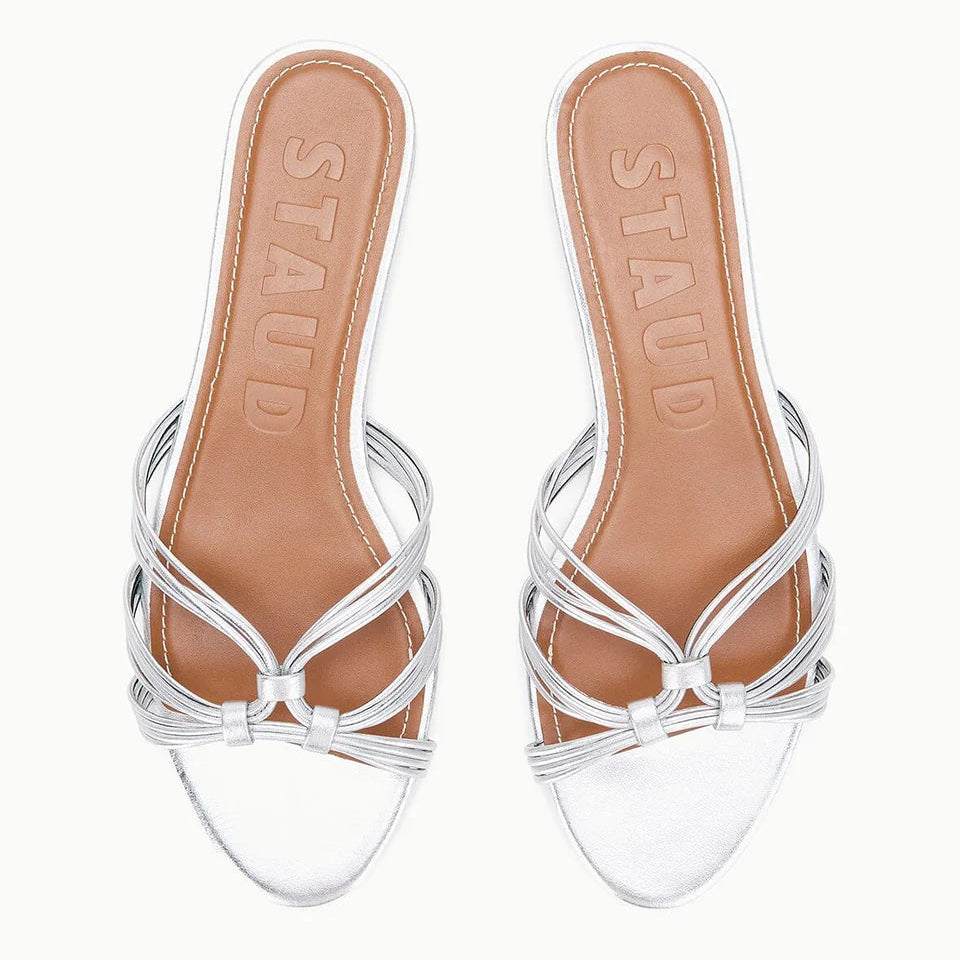 The Carrie Sandal by Staud features refined silver straps, tan leather insoles, and "STAUD" embossed on the footbed.