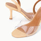 The Staud Brigitte Heel is a beige sandal featuring clear PVC straps, a slim high heel, and a chic slingback design, shown against a white background.