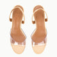 The Brigitte Heel by Staud features tan slingback sandals with clear straps and "Staud" embossed on the insoles, shown from above against a white background.