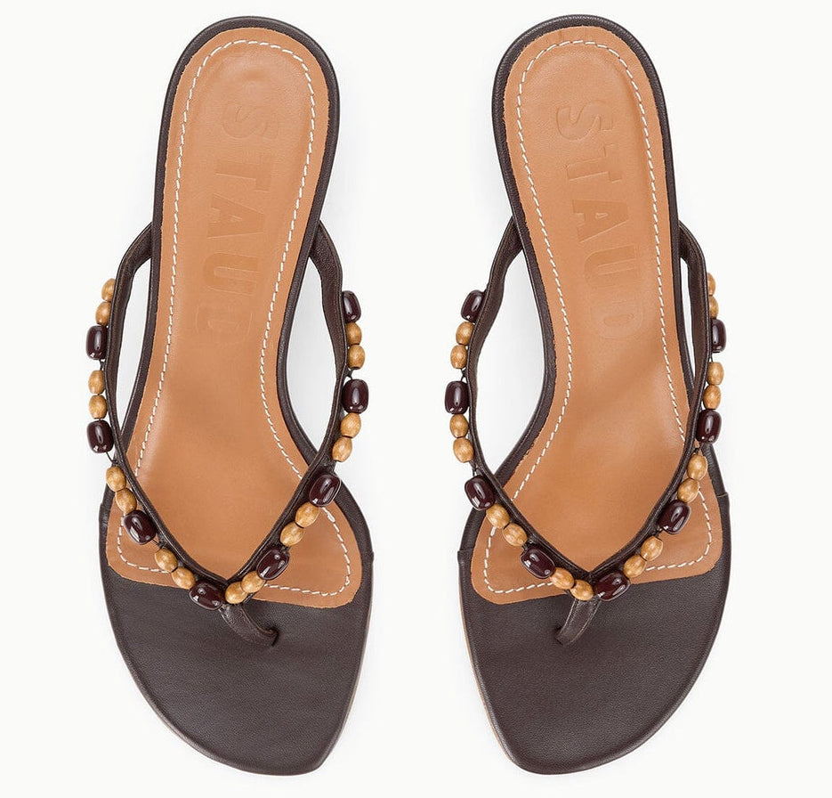 A pair of Staud Freja Thong Kitten Heel sandals in brown leather with tan insoles and decorative wooden beads on the straps, shown from above.